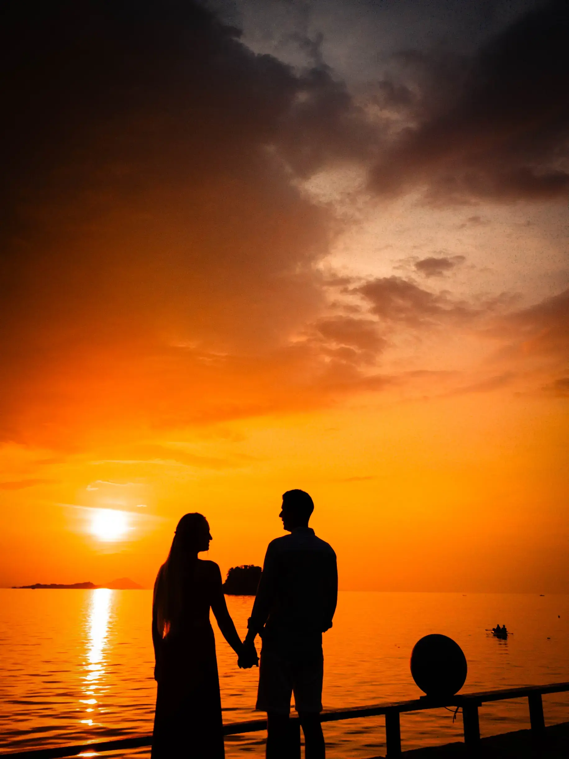 Silhouette of Andrei and Cristina holding hands at sunset by the sea