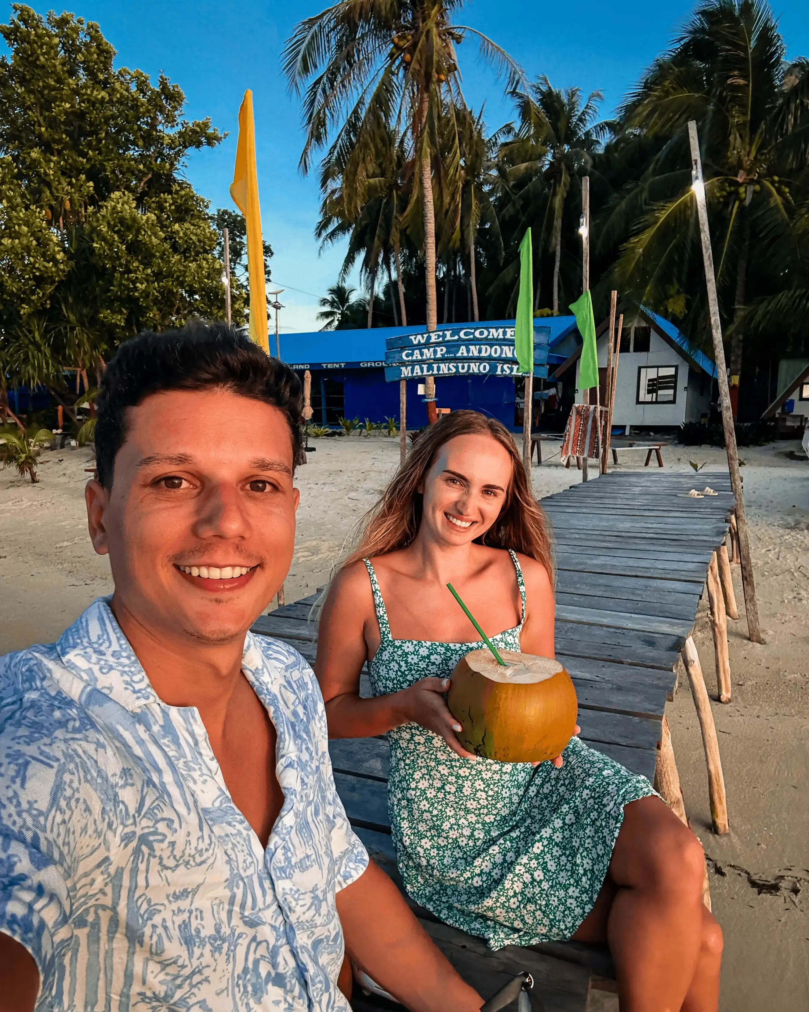 Andrei and Cristina on a boardwalk on a Philippine island with a coconut