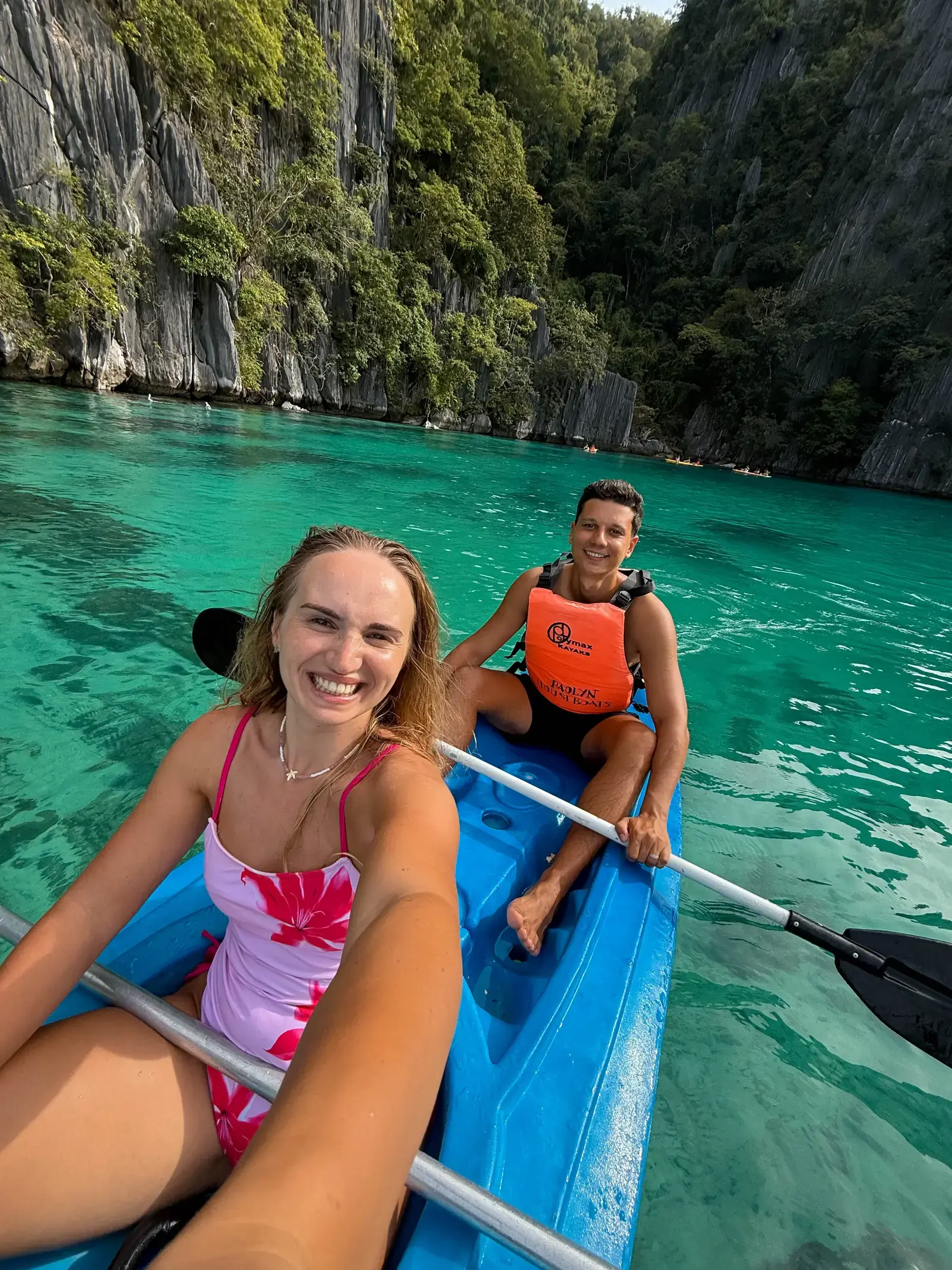 Andrei and Cristina kayaking in a turquoise lagoon surrounded by limestone cliffs
