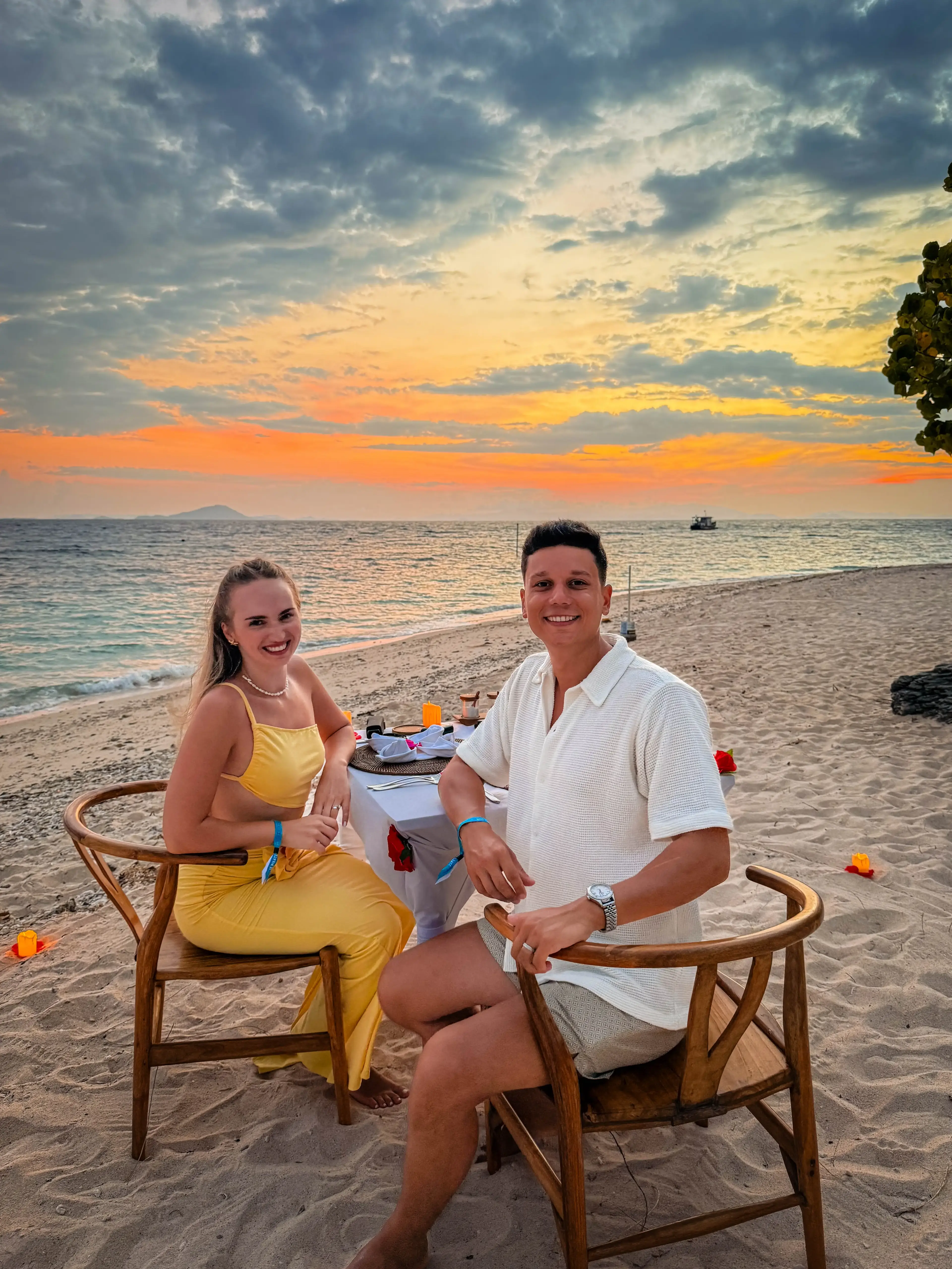 Andrei and Cristina at a beachside sunset dinner with candles