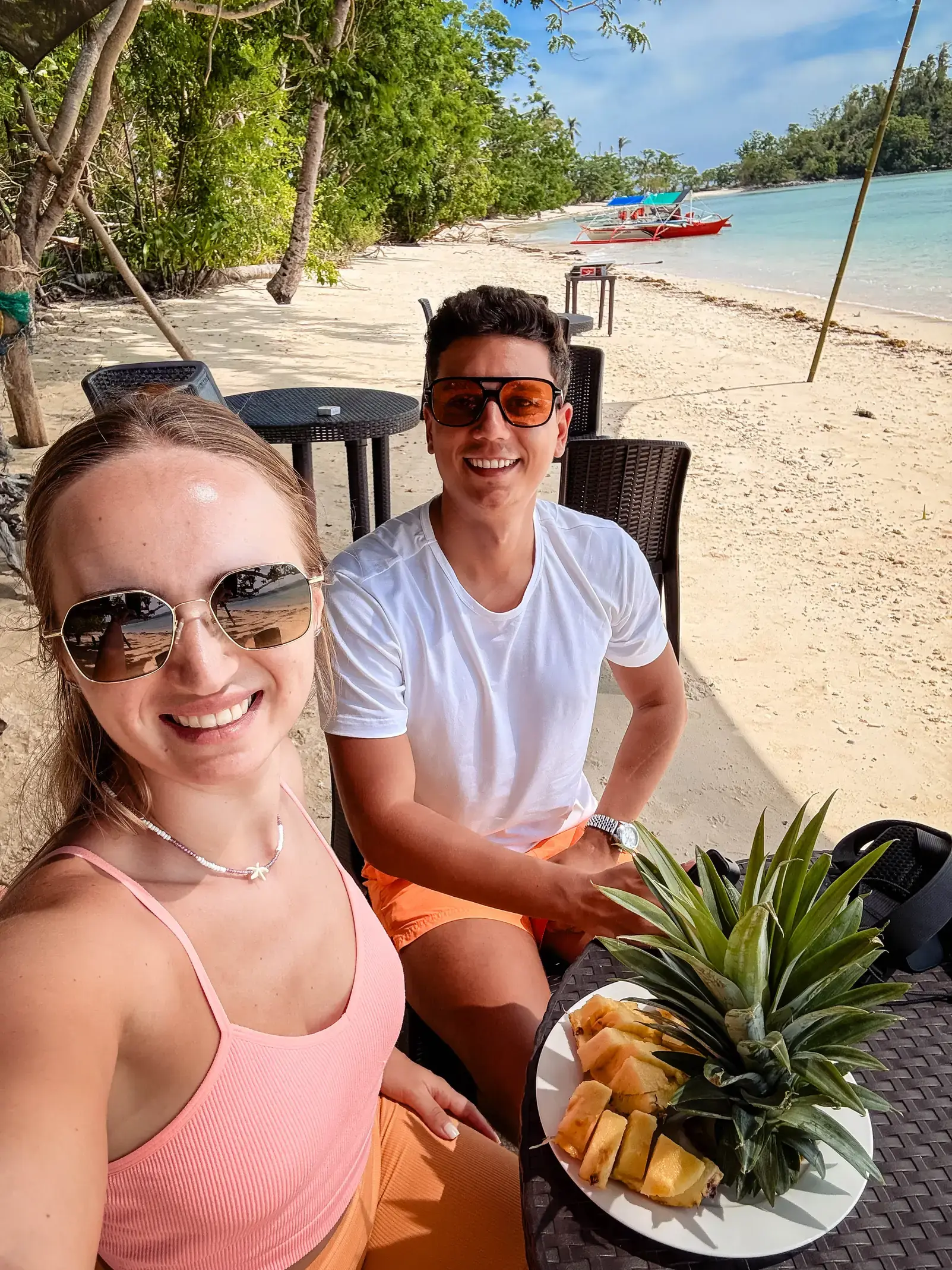 Andrei and Cristina enjoying fresh pineapple on a beach in the Philippines